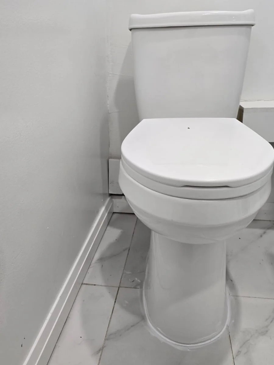 White toilet fixture beside a vanity on light floor tile